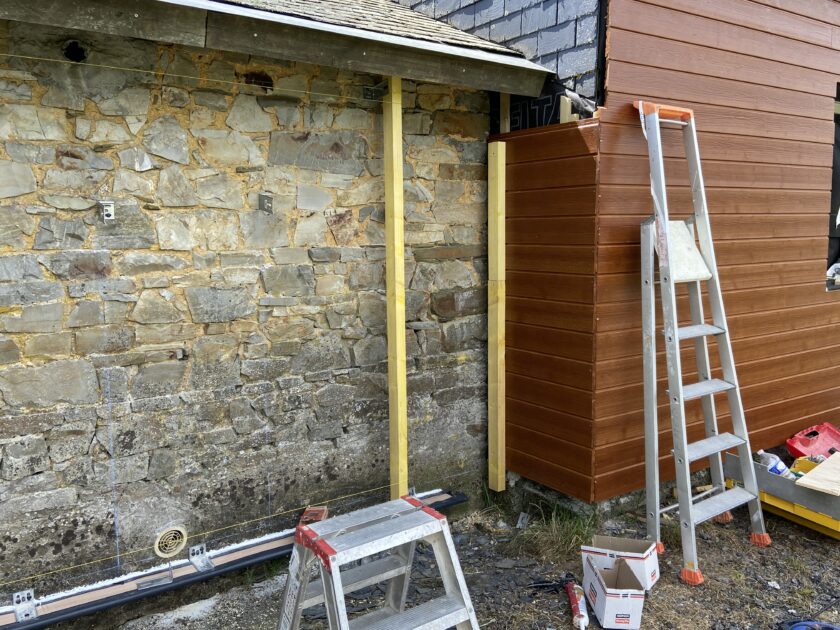 mur en pierre d'une maison en cours d'isolation avec bardage de bois