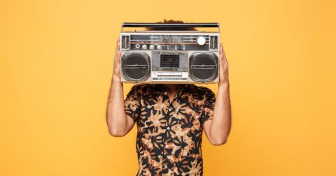 homme en chemise bariolée tenant un vieux poste de radio devant sa tête