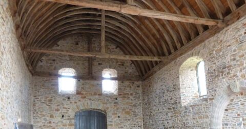 intérieur d'une chapelle en pierre avec charpente en bois apparente