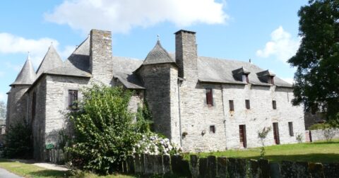 manoir en pierre au milieu d'un jardin arboré