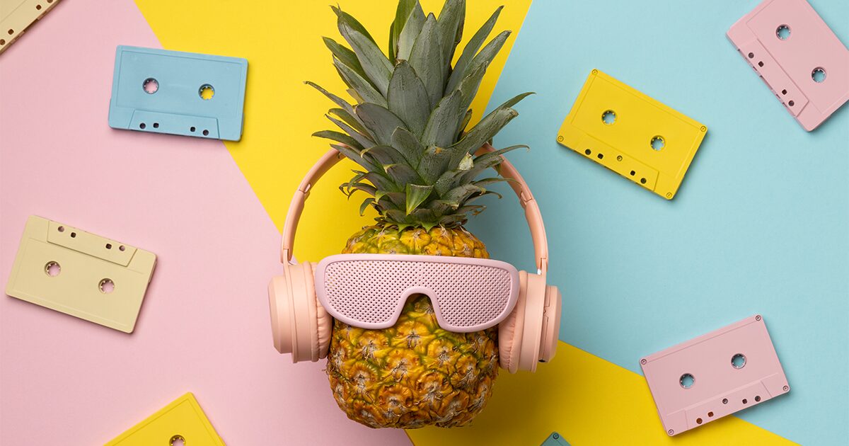 ananas avec un casque de musique et des lunettes de soleil rose sur un fond coloré avec vieilles cassettes