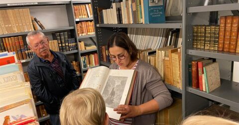 médiathécaire montrant de vieux livres dans les réserves