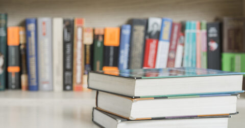 livres alignés sur une étagère et 3 livres posés devant en gros plan