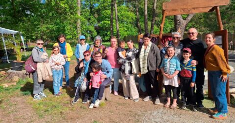 groupe d'adultes et d'enfants de tous âges posant pour une photo dans un parc arboré
