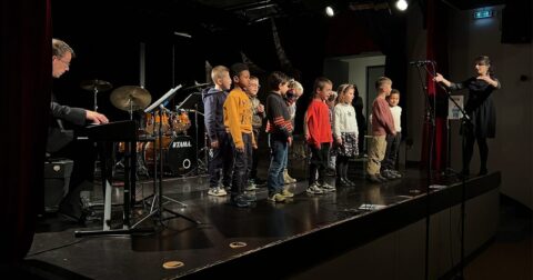 groupe d'enfants debout sur scène chantant