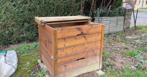composteur en bois posé au fond d'un jardin