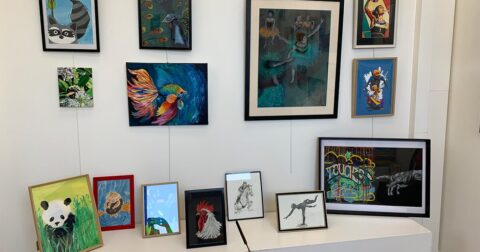 tableaux et toiles de peinture accrochées sur un mur blanc et posées sur un meuble bas