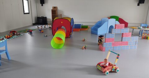 parcours de motricité, chariot de marche, jouets sur le sol d'une salle de jeux