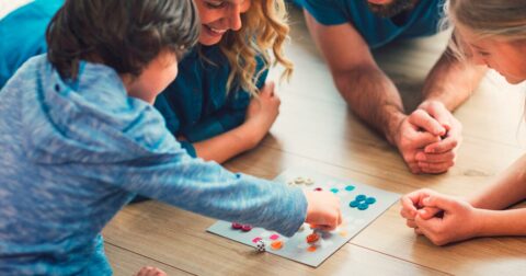 Famille de 4 personnes rigolant autour d'un jeu de société