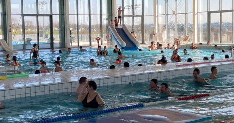 Nombreux baigneurs, enfants et adultes dans le bassin intérieur de la piscine