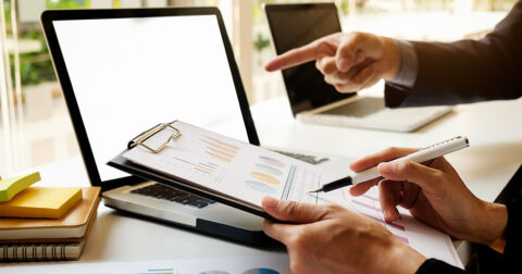 mains de deux hommes regardant un écran d'ordinateur portable et des graphiques