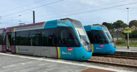 deux Tram Trains gris, bleu clair, jaune et violet à quai