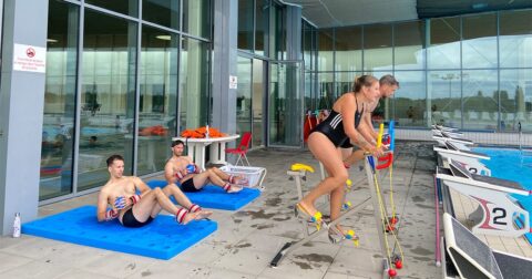 hommes et femmes en maillot de bain faisant du vélo et de la musculation au bord d'une piscine extérieure