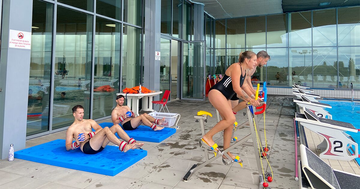 hommes et femmes en maillot de bain faisant du vélo et de la musculation au bord d'une piscine extérieure