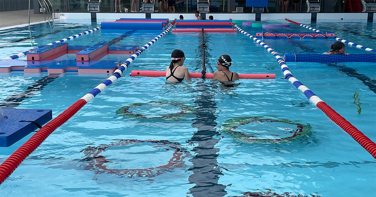 deux filles passant sous des obstacles dans une piscine extérieure