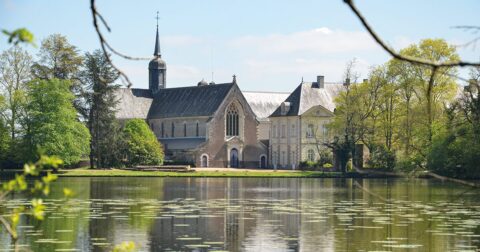 Vue de l'abbaye de la Melleray se reflétant dans un étang aux beaux jours