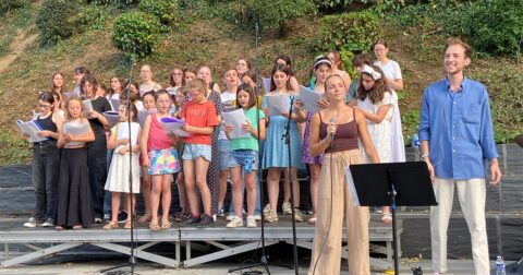 chorale d'enfants sur scène en extérieur avec leur professeur