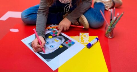 un enfant assis sur le sol fait du coloriage