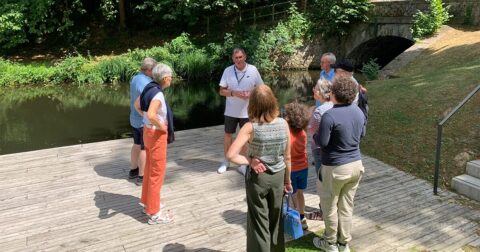 groupe de personnes au bord d'un cours d'eau écoutant un guide