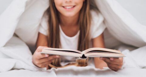 jeune fille allongée sur le ventre lisant un livre