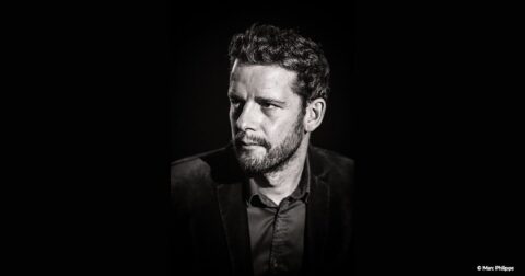 Portait noir et blanc d'une homme avec cheveux courts, barbe et costume