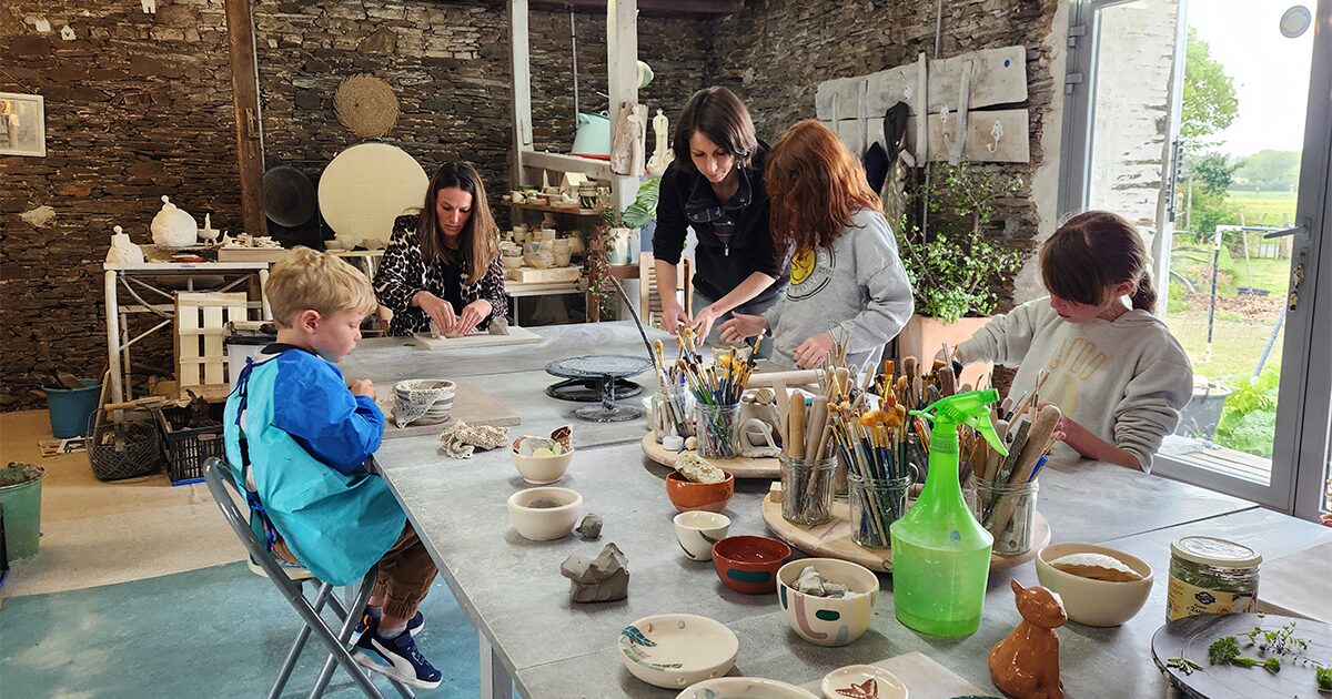 groupe d'adultes et d'enfants dans un atelier de poterie apprenant le modelage