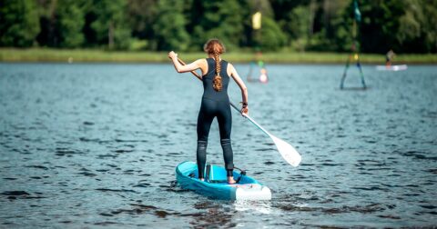 femme de dos faisant du paddle sur un lac