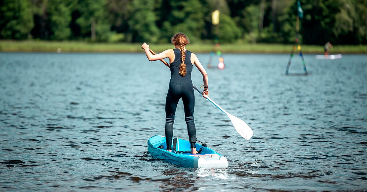 femme de dos faisant du paddle sur un lac