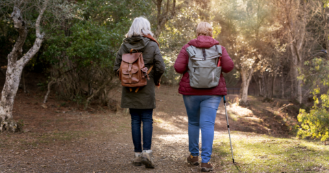 deux femmes séniors de dos avec un sac marchant dans la nature