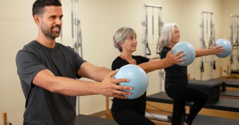 un coach avec deux retraitées faisant de la gym douce avec ballon