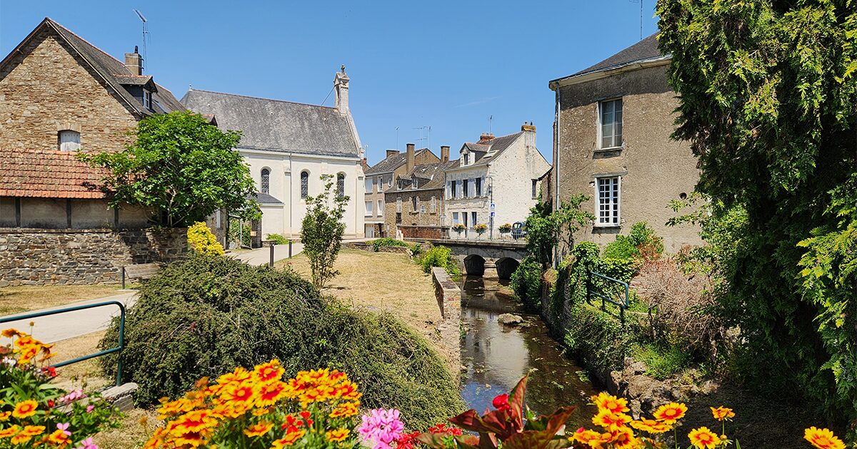 Rivière bordée de vieilles maisons et d'un pont fleuri