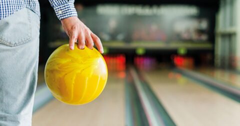 homme tenant une boule de bowling jaune sur la piste