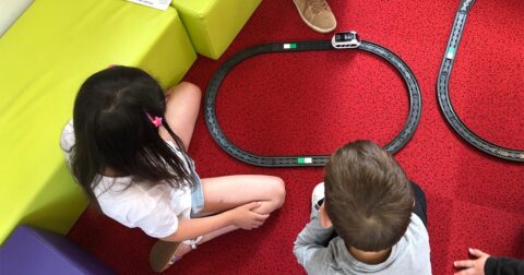 deux enfants assis sur un tapis jouant avec un circuit de train