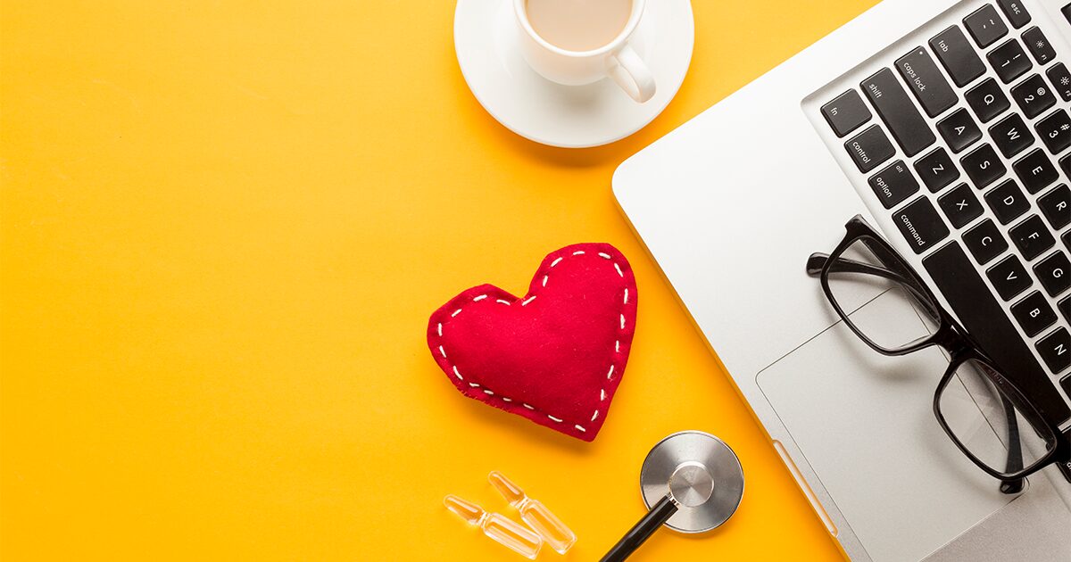 Ordinateur portable posé sur une table avec un cœur rouge et une tasse de café