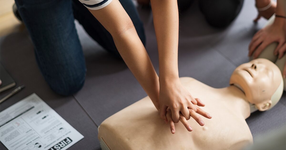personne effectuant un massage cardiaque sur un mannequin
