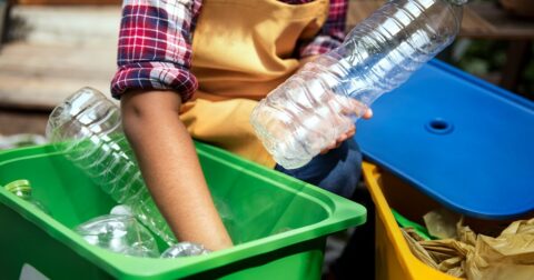 une femme trie ses déchets entre deux poubelles