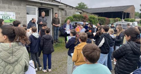Un éleveur s'adressant à un groupe de collégiens qui attendent devant sa ferme.