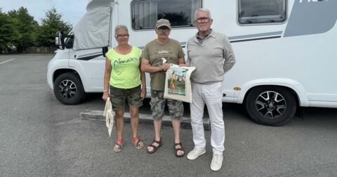 3 personnes posant devant un camping-car. L'une d'elles tient un sac en tissu.