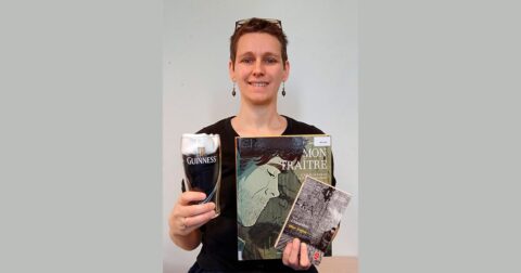 portrait d'une femme aux cheveux courts tenant une sélection de 3livres