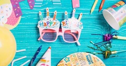 lunettes et décorations d'anniversaire posées sur une table bleue