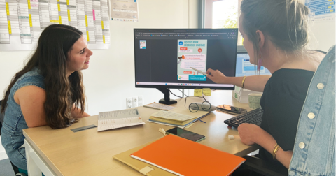 deux femmes derrière un bureau regardant ensemble un écran