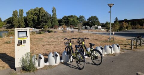 Deux vélos à assistance électriques stationnés à une station de location au bord de l'étang de Choisel
