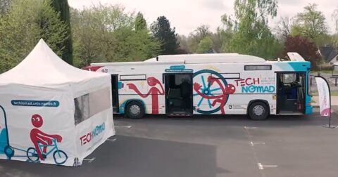 Un car stationné sur un parking et un barnum pour accueillir le public.