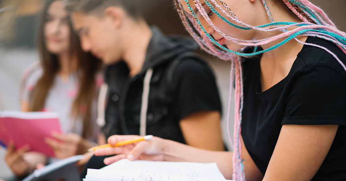 jeunes assis dehors écrivant sur un cahier