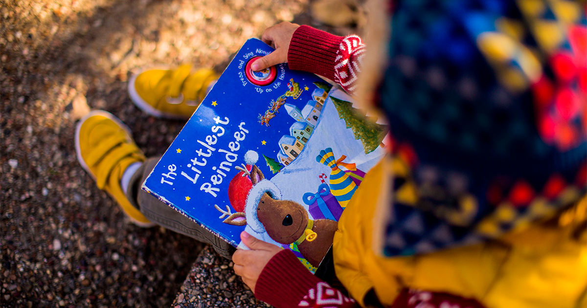 Enfant lisant un livre au pied d'un arbre en automne