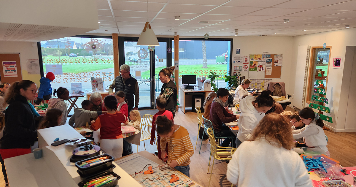 Adultes et enfants dans un hall préparant des décorations de Noël sur des tables